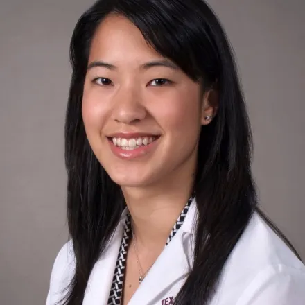 A professional portrait of Dr. Joyce Li smiling with a gray background
